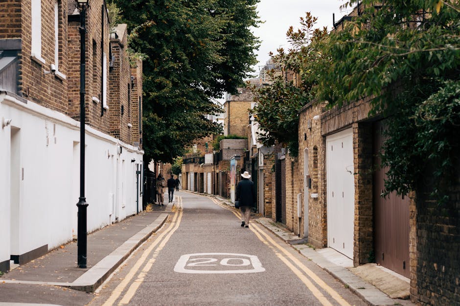 A narrow street in Canonbury Terrace lined with residential brick buildings, some with white painted lower walls and others with exposed brick facades. The street features a double yellow line on eith